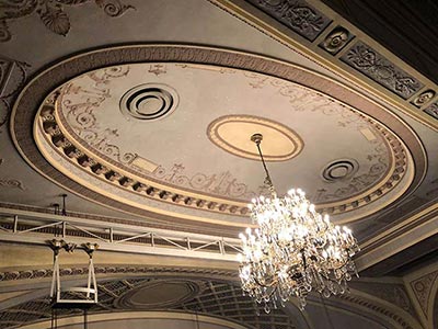 劇場内に明かりを灯す大きなシャンデリアとアダム様式が使用された天井の様子